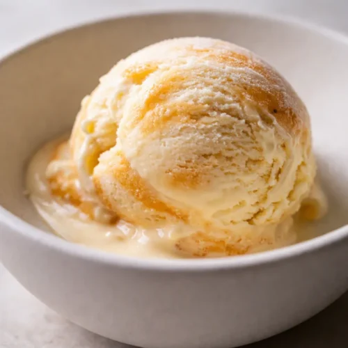 Scoops of orange creamsicle ice cream in a white bowl, creamy texture with swirled orange and vanilla colors
